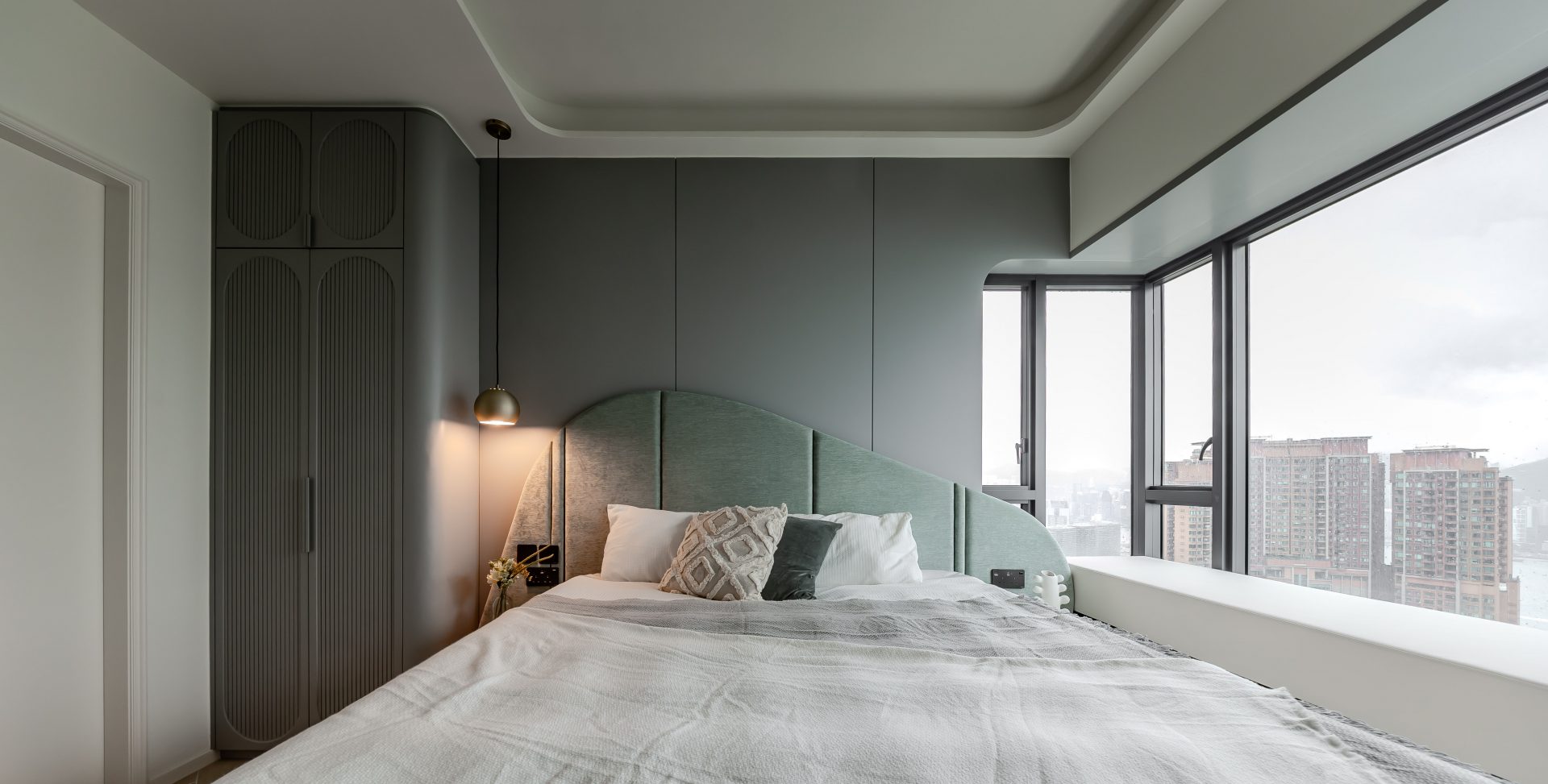 ED Design 主臥住宅案例，設有灰綠色弧形床頭、全高收納與轉角窗景